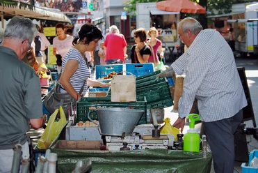 Farmers’ market in Deutz Market scene with people inspecting and buying fresh fruit and vegetables at a stall in Cologne.