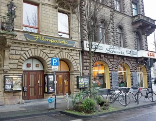 Filmpalette Ansicht des Filmtheaters "Filmpalette" in Köln, eingefasst von historischen Steingebäuden, bei grauem Wetter.