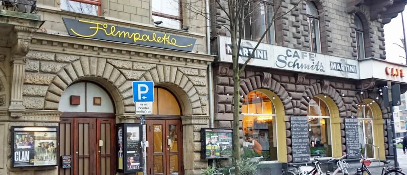 Filmpalette Ansicht des Filmtheaters "Filmpalette" in Köln, eingefasst von historischen Steingebäuden, bei grauem Wetter.