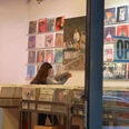 Parallel Schallplatten Ein Schallplattenladen mit offenen Türen zeigt eine Person, die im Inneren Schallplatten durchstöbert.A record store with open doors shows a person browsing through records inside.