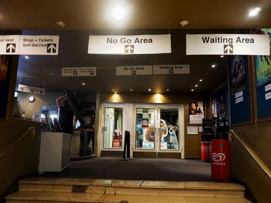 Metropolis Eingangsbereich eines Kinos mit beleuchteten Schildern, die die verschiedenen Bereiche kennzeichnen.Entrance area of a movie theater with illuminated signs indicating the different areas.