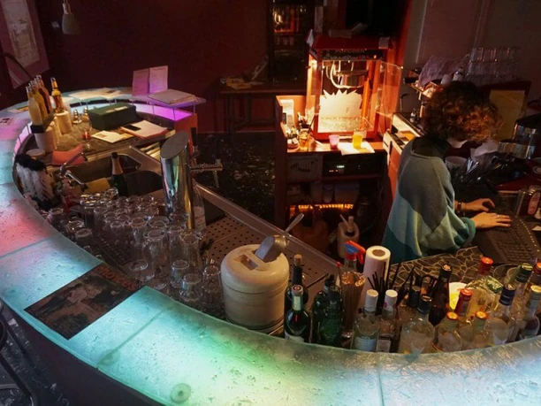 TURISTARAMA An elegant bar area with colorful lighting shows a person working on a laptop.