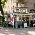 Köski Royal Ein charmanter Kiosk mit dem Schriftzug "KÖSKI ROYAL", umgeben von städtischem Grün in einer urbanen Umgebung.A charming kiosk with the lettering "KÖSKI ROYAL", surrounded by urban greenery in an urban environment.