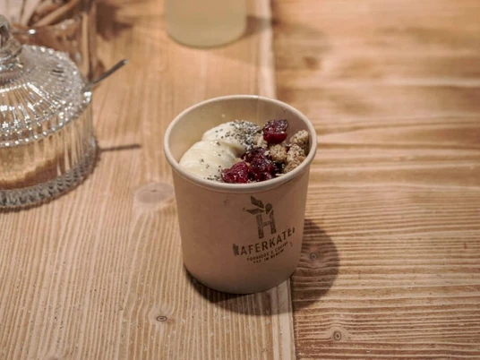 Haferkater Ein Haferbrei mit Früchten und Zimt zum Mitnehmen in einem Pappbecher.A bowl of porridge with fruit and cinnamon to go, in a paper cup.