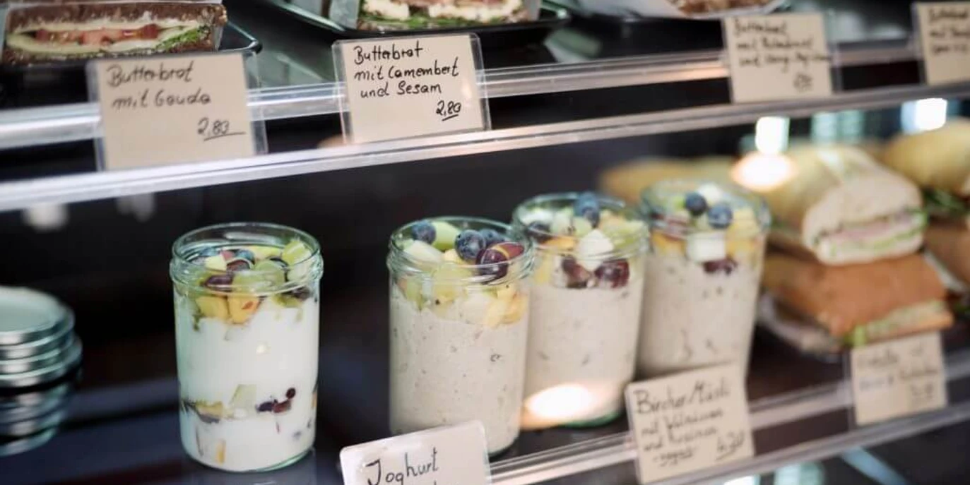 Cafe Einspänner Nahaufnahme der Vitrine mit kleinen Gläschen gefüllt mit Jogurt und Obst. Close-up of the display case with small jars filled with yogurt and fruit.