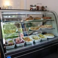 Cafe Frau Maaß Herr Schlie Glasvitrine mit herzhaften Quiche und Salaten. Glass display case with savory quiche and salads.