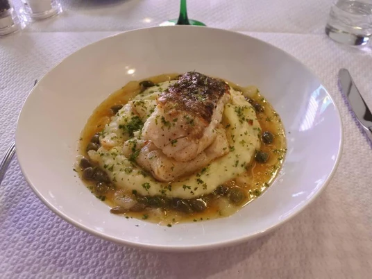 Wackes Ein Teller mit gebratenem Fischfilet auf cremigem Kartoffelpüree, garniert mit Kapern und Kräutern.A plate with pan-fried fish fillet served on creamy mashed potatoes, garnished with capers and herbs.