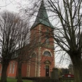 Kirche im Dorf Intschede, umgeben von kahlen Bäumen im Herbst, mit markantem grünen Kirchturm.