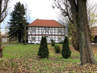 Amtshaus Wölpe Das Bild zeigt ein historisches Fachwerkhaus im Grünen mit kleinen Koniferen im Vordergrund.