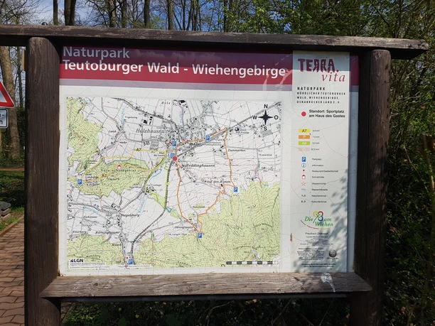 Informationstafel am Sportplatz Bad Holzhausen Informationstafel im Naturpark Teutoburger Wald mit detaillierten Wanderrouten und Orientierungshilfen.