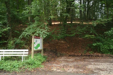 Wanderparkplatz am Waldrand mit Infotafel und Bank; von Bäumen umgeben, Ausgangspunkt für Wanderwege.