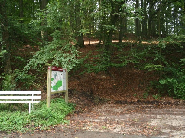 Wanderparkplatz am Waldrand mit Infotafel und Bank; von Bäumen umgeben, Ausgangspunkt für Wanderwege.