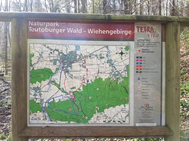 Informationstafel mit Wanderwegen im Naturpark Teutoburger Wald - Wiehengebirge auf hölzernem Rahmen.