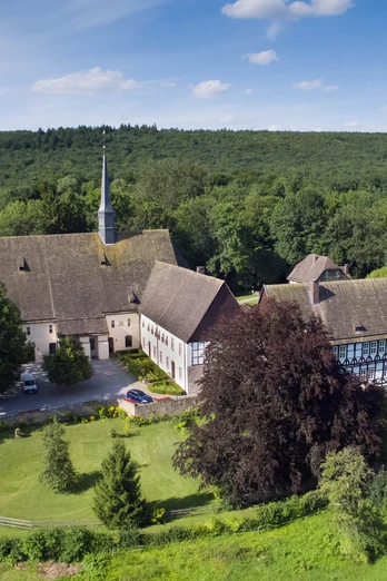 Luftaufnahme des Klosters Falkenhagen inmitten grüner Wälder unter einem klaren blauen Himmel.