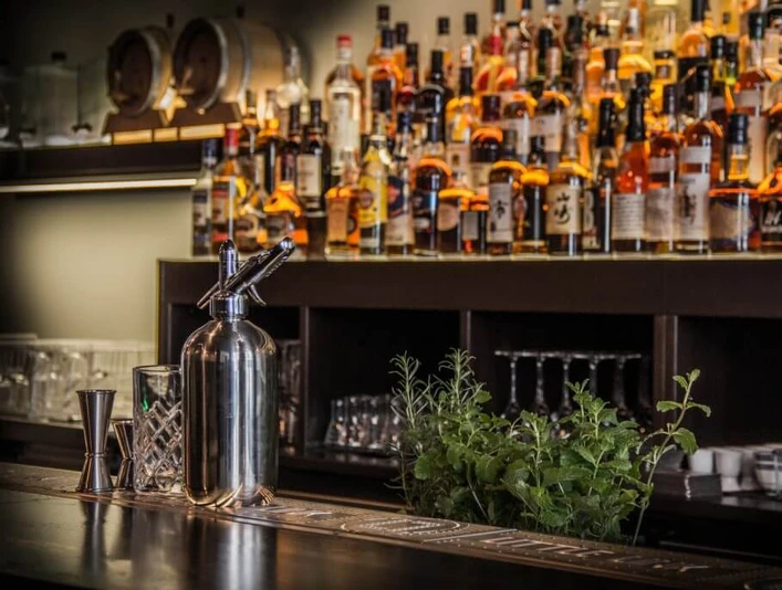 Bar Little Link Blick über die Bartheke an die mit Flaschen bestückte Regalwand.View across the bar counter to the wall of shelves stocked with bottles.