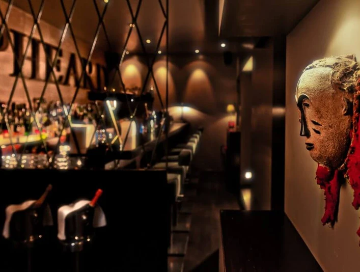 Samuel's Shep Eine stilvolle Bar mit einer kunstvollen Maske an der Wand. Die Bar ist elegant beleuchtet und lädt zu einem entspannten Abend ein.A stylish bar featuring an artistic mask on the wall. Elegantly illuminated, the bar invites guests for a relaxed evening.