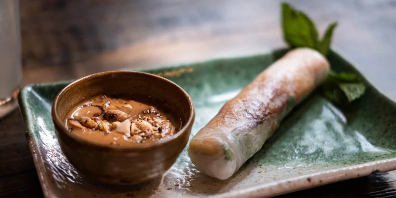 Chum Chay Sommerrolle auf einem grünen Teller mit Erdnusssoße Summer roll on a green plate with peanut butter dip