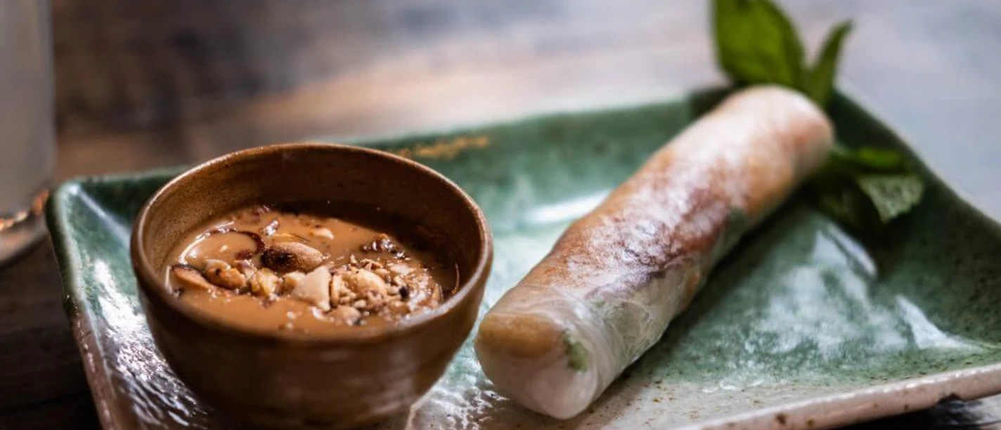 Chum Chay Sommerrolle auf einem grünen Teller mit Erdnusssoße