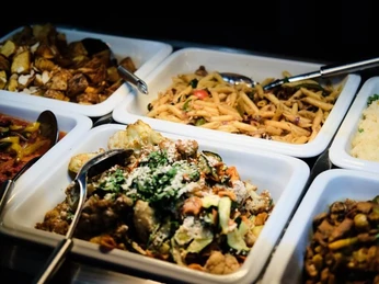 Sattgrün Eine Auswahl an Speisen in Buffet-Schalen, darunter Pasta, Kartoffeln und Gemüsegerichte.A selection of dishes presented in buffet trays, including pasta, potatoes, and vegetable options.