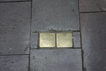 Stolpersteine Zwei Messingplatten inmitten von Bürgersteigpflaster gedenken Opfern des Nationalsozialismus.
