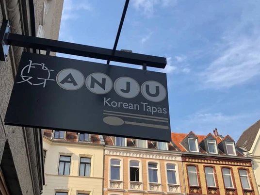 Restaurant Anju, Schild Ansicht auf eine Häuserfassade mit Restaurantschild. View of a house facade with a restaurant sign.