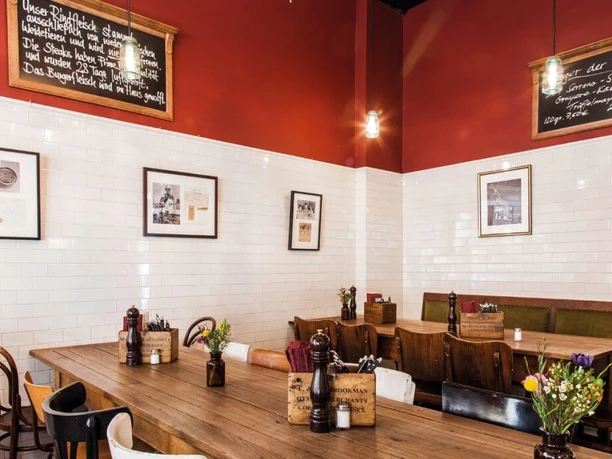 Die fette Kuh Rustic wooden tables in a room with white tiles and red walls.