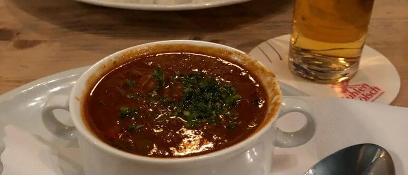 Pütz Brewery A delicious dish of hearty goulash and bread, accompanied by a refreshing beer.