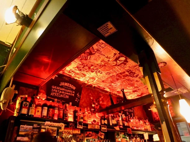 Frieda Bar Bar in rotem Licht beleuchtet mit Aufklebern an der Decke.