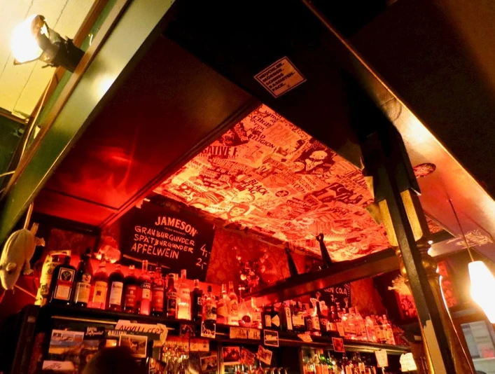 Frieda Bar Bar in rotem Licht beleuchtet mit Aufklebern an der Decke. Bar in red light illuminated with stickers on the ceiling.