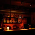 Pegel Auf dem Bild zeigt sich eine stimmungsvoll beleuchtete Bar mit einer Reihe von Flaschen und Gläsern hinter dem Tresen. Warme Lichter schaffen eine einladende Atmosphäre.The picture shows an atmospherically lit bar with a row of bottles and glasses behind the counter. Warm lights create an inviting atmosphere.