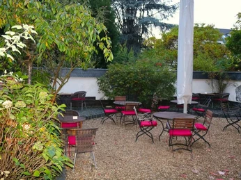 Traubenzeit Ein gemütlicher Sommergarten mit roten Stühlen, runden Tischen und einer Sonnenschirmumrandung auf Kiesboden.A charming summer garden featuring red chairs, round tables, and bordered by sun umbrellas, all placed on a gravel surface.