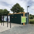 Toilette am Wohnmobilstellplatz Bruchhausen-Vilsen Grüne Sanitäranlage an einem Wohnmobilstellplatz mit Informationsschild und gepflastertem Vorplatz.