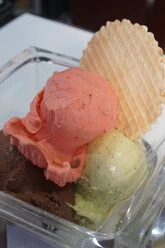 IL GELATO di ferigo Close-up of three scoops of ice cream with a round cone.
