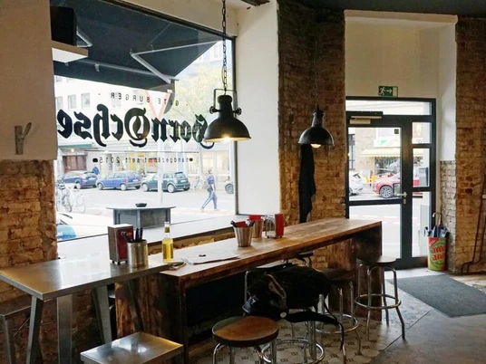 Burger Restaurant Hornochse Im industriellen Stil eingerichtetes Restaurant mit Backsteinwand und metallischen Hängeleuchten.Restaurant furnished in an industrial style with brick wall and metallic pendant lights.