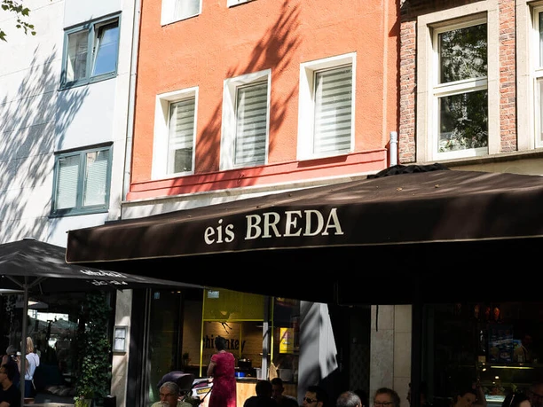 Breda Ice Cream Café People are sitting under a large sunshade with the inscription eis Breda and eating ice cream.