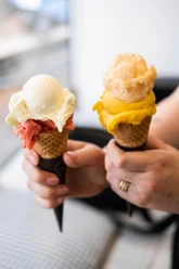 Eisdiele Keiserlich Nahaufnahme, eine Person hält zwei Waffelhörnchen mit jeweils zwei Kugel Eis in die Kamera.