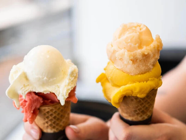 Eisdiele Keiserlich Nahaufnahme, eine Person hält zwei Waffelhörnchen mit jeweils zwei Kugel Eis in die Kamera.