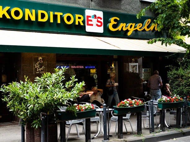 Konditorei Eis Engel Facade with awning and sign placed in large letters above the awning. People sitting in front of the cafe.