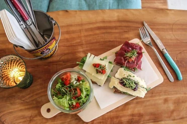 Cafe Geschnitten Brot Auf einem Holzbrettchen liegen drei schön belegte Brote und ein kleiner Salat in einem Glas Schüsselchen.