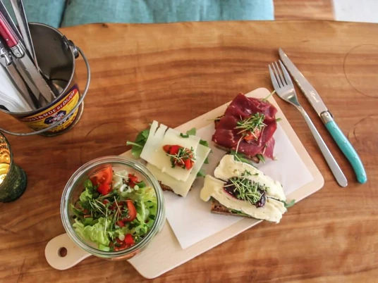 Cafe Geschnitten Brot Auf einem Holzbrettchen liegen drei schön belegte Brote und ein kleiner Salat in einem Glas Schüsselchen. Three tasty sandwiches and a small salad in a glass bowl on a wooden board.