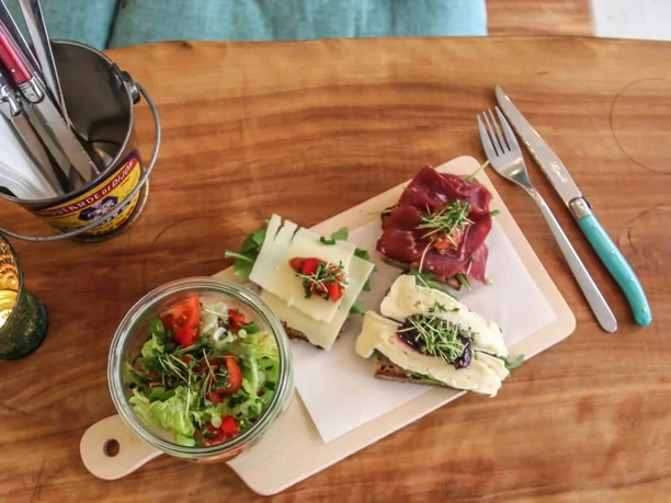 Cafe Geschnitten Brot Three tasty sandwiches and a small salad in a glass bowl on a wooden board.