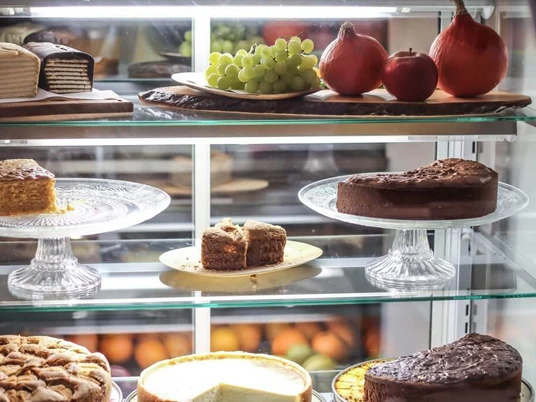 Cafe Geschnitten Brot Glasvitrine befüllt mit Kuchen auf Kuchenplatten aus Glas.Glass display case filled with cakes on glass cake plates.