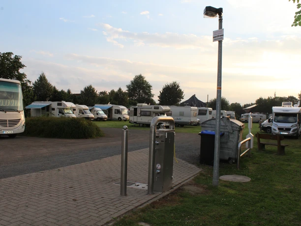 Wohnmobilstellplatz Bruchhausen-Vilsen Wohnmobilstellplatz in einer grünen Umgebung mit mehreren Reisemobilen, gepflasterten Wegen und Laterne.