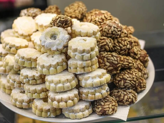 Simitzade Vielzahl von feinen Gebäckstücken, darunter mit Puderzucker bestäubte Kekse und mit Samen bedeckte Cookies auf einem Teller angerichtet.An assortment of delicate pastries arranged on a plate, including powdered sugar-dusted biscuits and cookies topped with seeds.