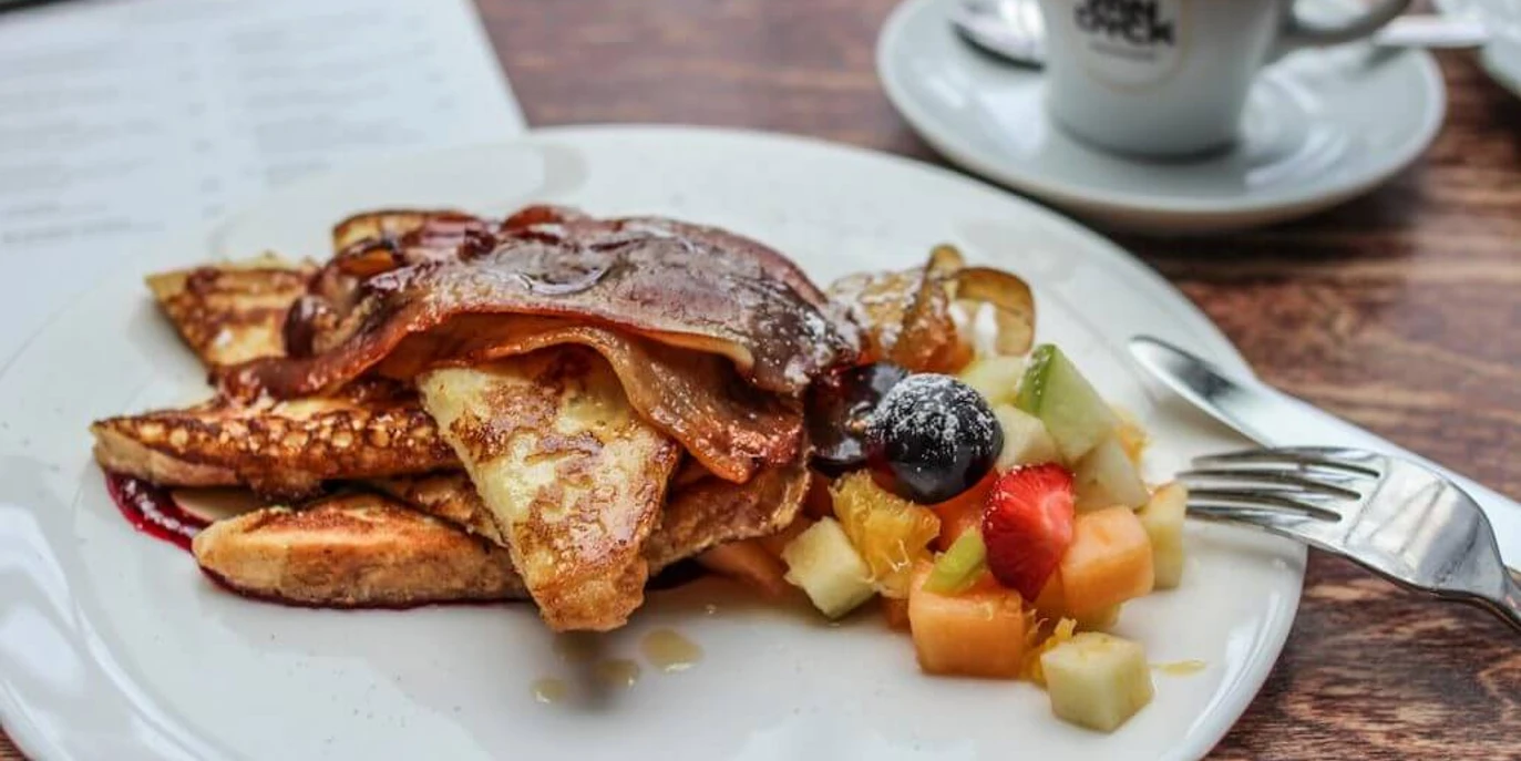 Cafe Sehnsucht French Toast mit frischem Obst und Speck, dazu eine Tasse KaffeeFrench Toast with fresh fruitand bacon, served with a cup of coffee