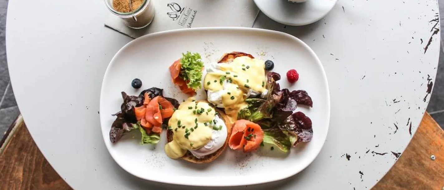 Hinz und Kunz Breakfast plate with egg benedict, salmon, salad and a black coffee.