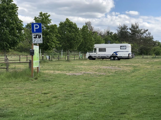 Leese WoMo Platz Wohnmobilstellplatz mit viel Grünflächen, Wohnmobil parkt, im Hintergrund Bäume und ein Parkplatzschild.