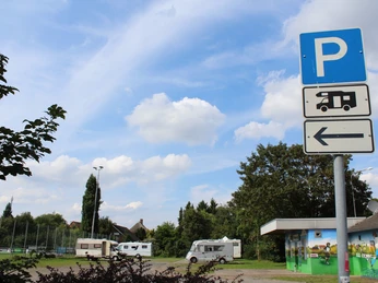 Stadt Petershagen Reisemobilstellplatz Wohnmobilstellplatz in Petershagen neben Sportanlage, mit Parkhinweisschild und blauem Himmel.