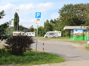 Stadt Petershagen Reisemobilstellplatz Reisemobilstellplatz in Petershagen mit Wohnmobilen auf asphaltierter Fläche vor bepflanzter Kulisse.