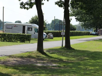 Reisemobilstellplatz in Rodewald mit gepflastertem Weg, Wohnmobil und gepflegten Grünanlagen.